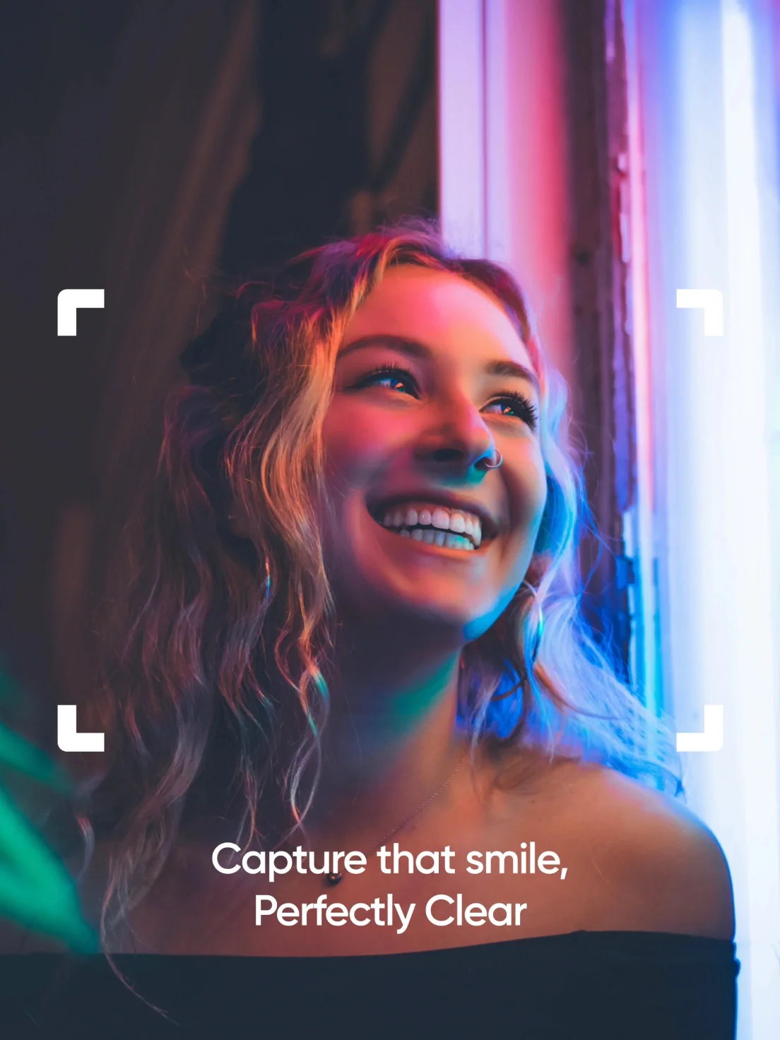 A smiling young woman with wavy hair is framed by colorful lights, showcasing Perfectly Clear's vibrant brand identity below her.