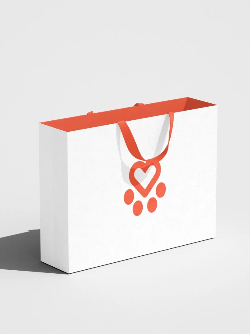 A white shopping bag with orange handles and a heart-paw design, reflecting Spanish Stray Dogs' brand identity, set against a light background.