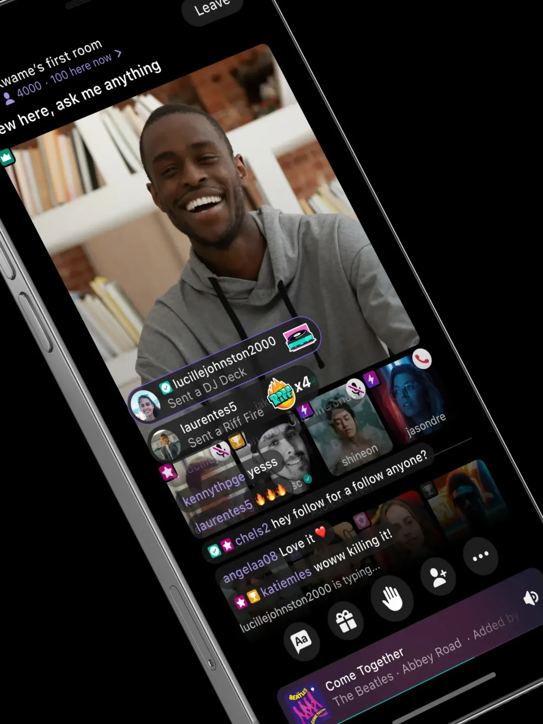A man smiles during a livestream on a social media app in dark mode, with colorful viewer comments and reactions displayed on the screen.