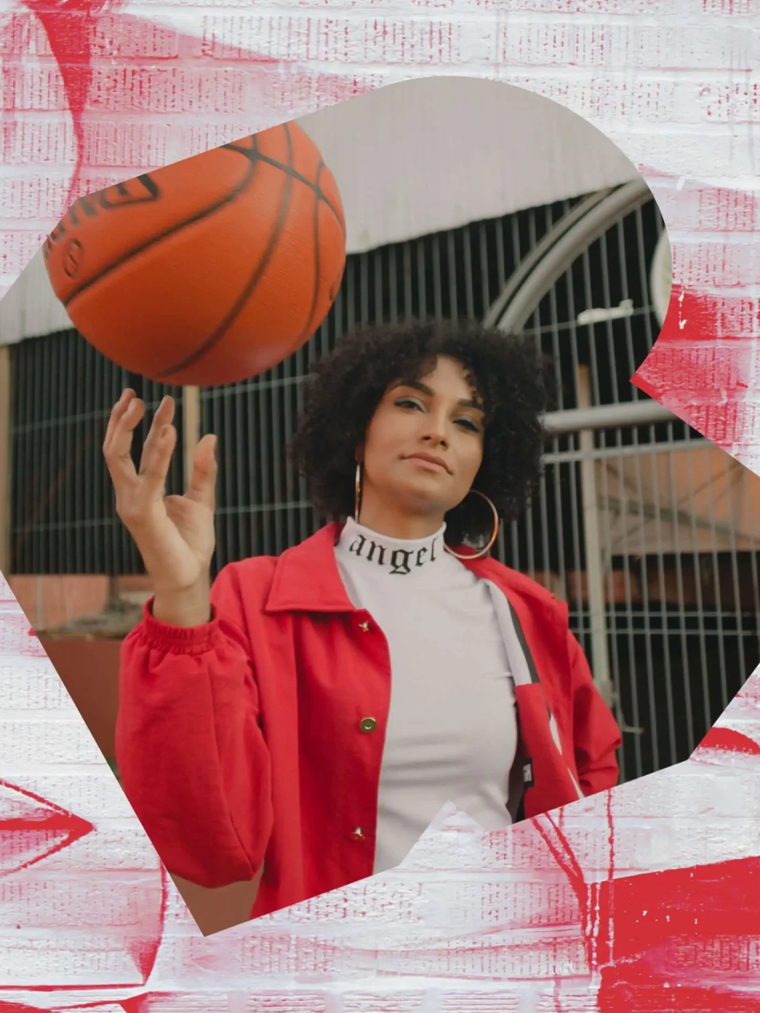 A person in a red jacket spins a basketball on their finger—riffing on unique brand identity in outdoor photography with a fence behind.