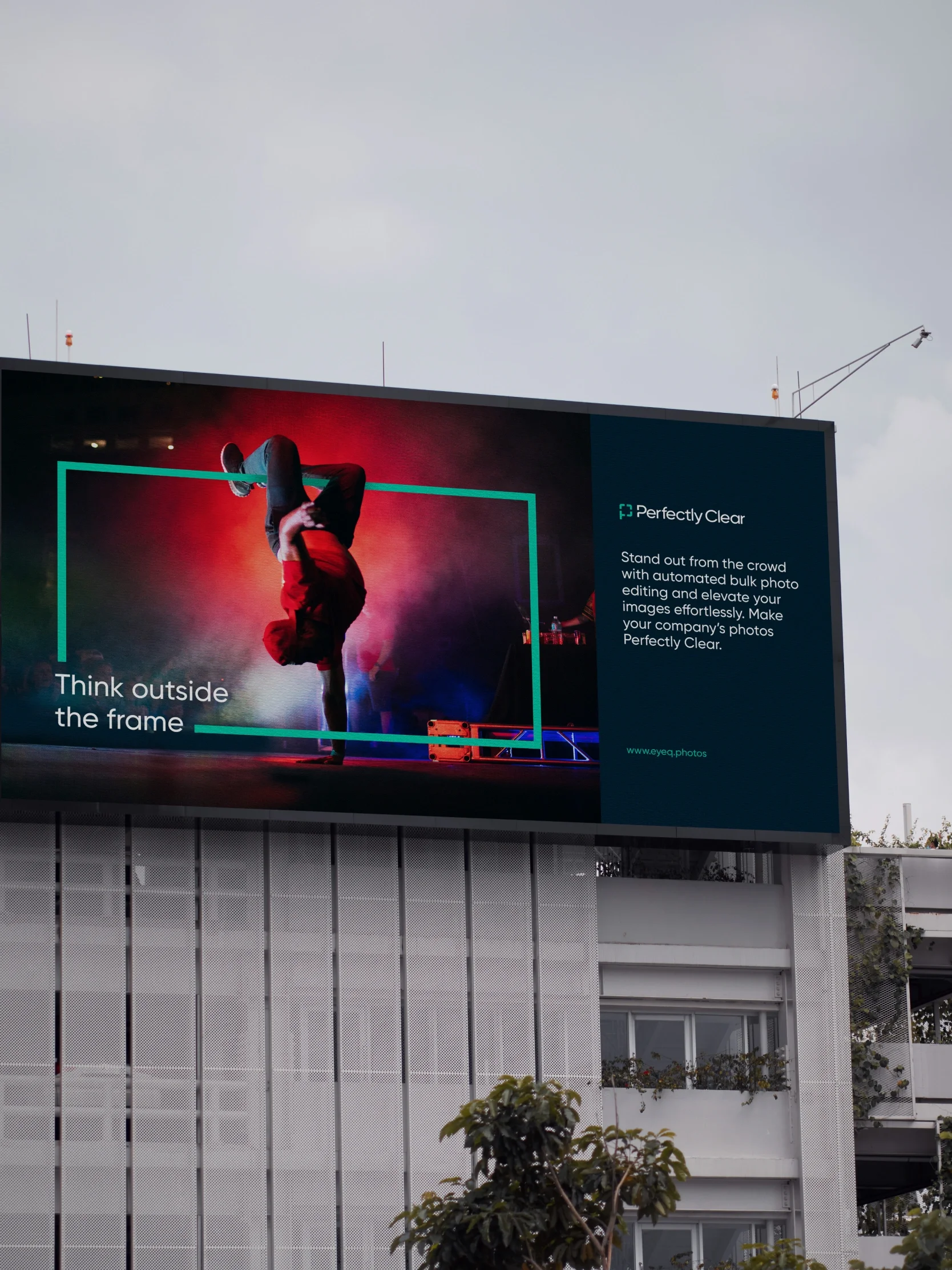 A billboard shows a breakdancer in vibrant lighting with the text Think outside the frame and a Perfectly Clear app design slogan for photo software.