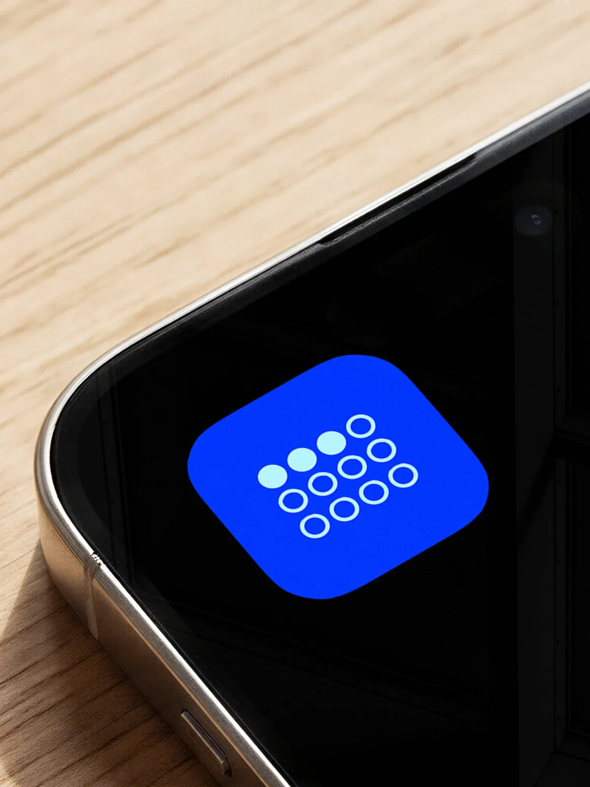 Collectivally app icon on a phone resting on a wooden table