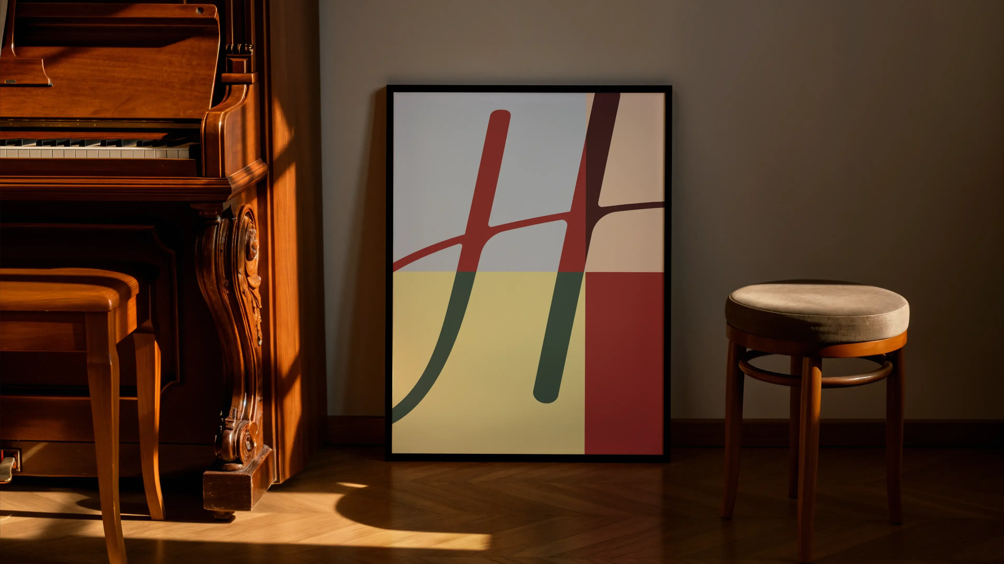 A framed poster leaning against a wall beside an upright piano. The H of the Hutton signature is enlarged and cropped across blocks of pale blue, cream, yellow and red