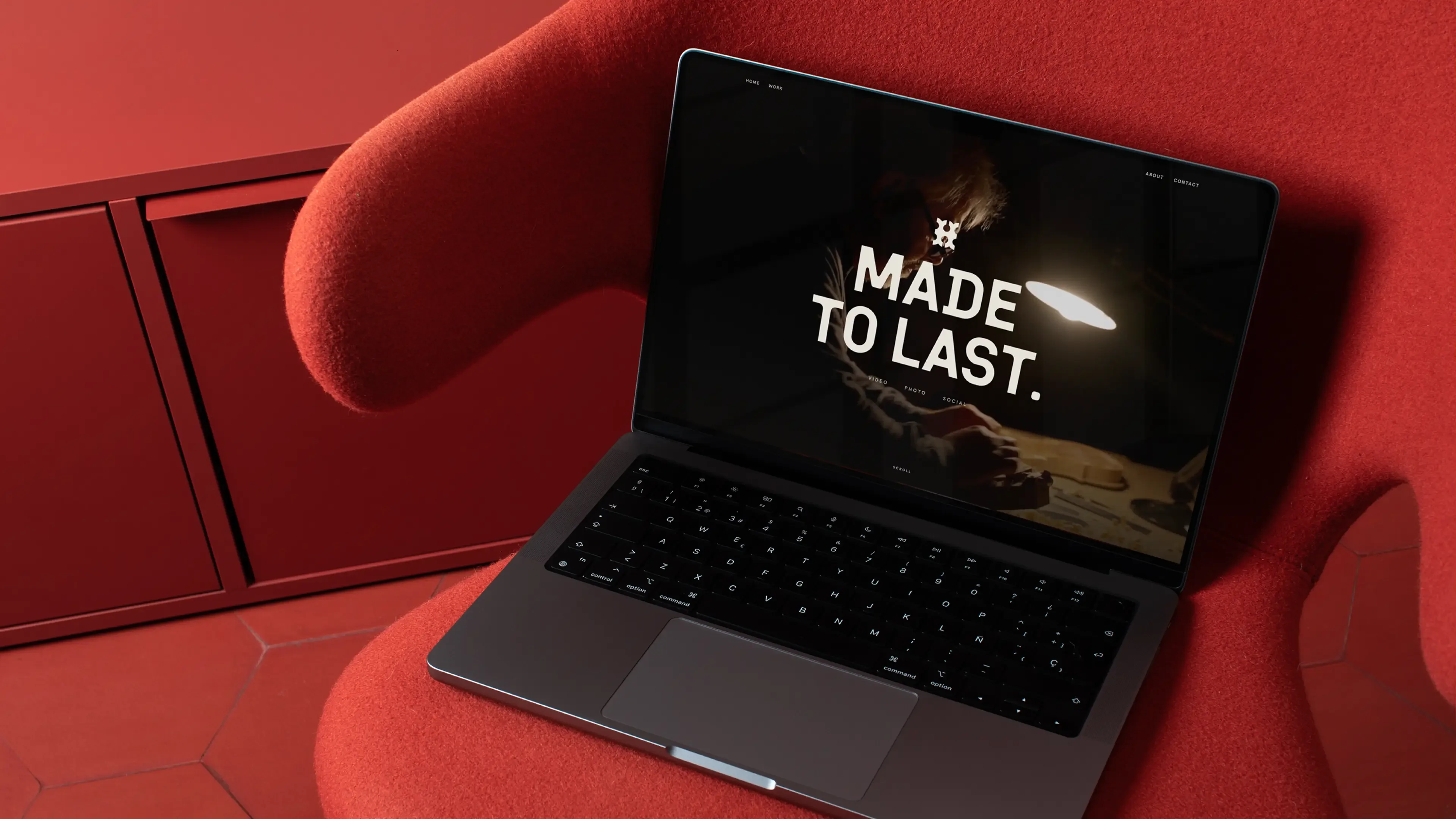 The Hutton website on a laptop resting on a red armchair. The homepage reads “Made to last.” over dark workshop footage